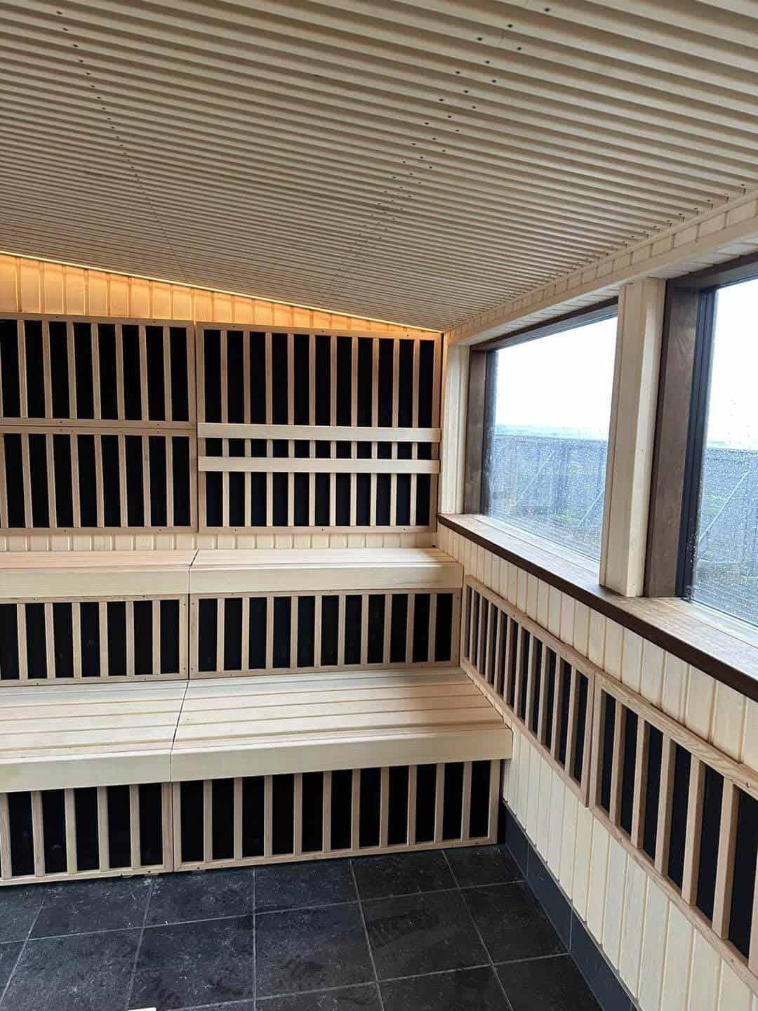 Udendørs sauna i asp træ med store vinduer og moderne design.