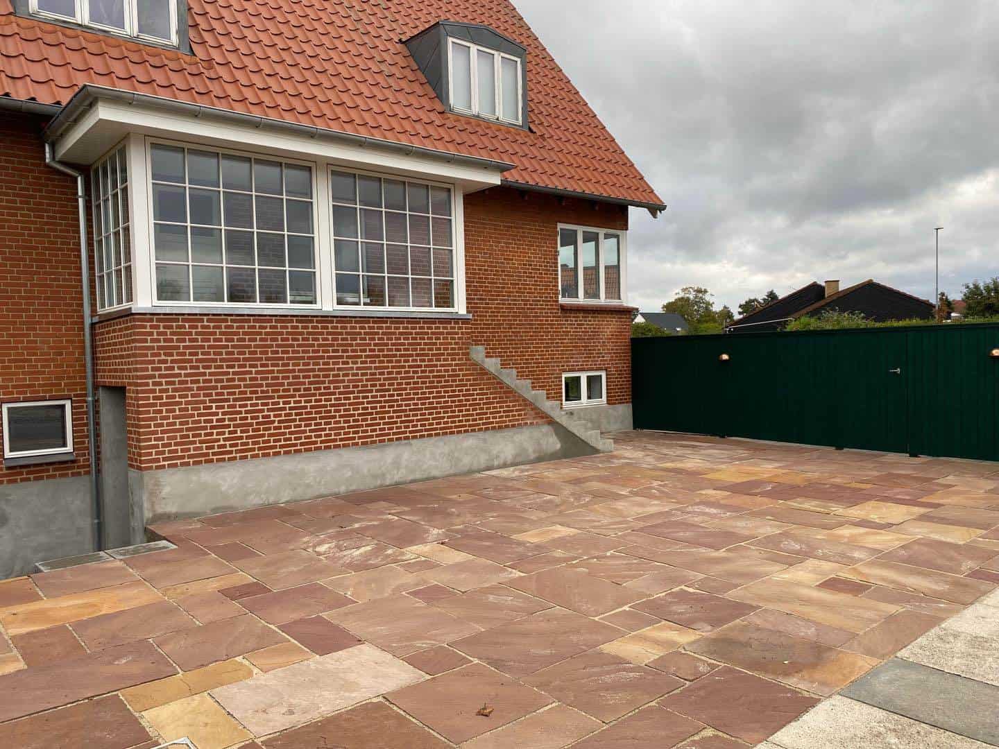 Nytrukket terrasse med Chelsea mønster, vindfang og plankeværk foran huset.