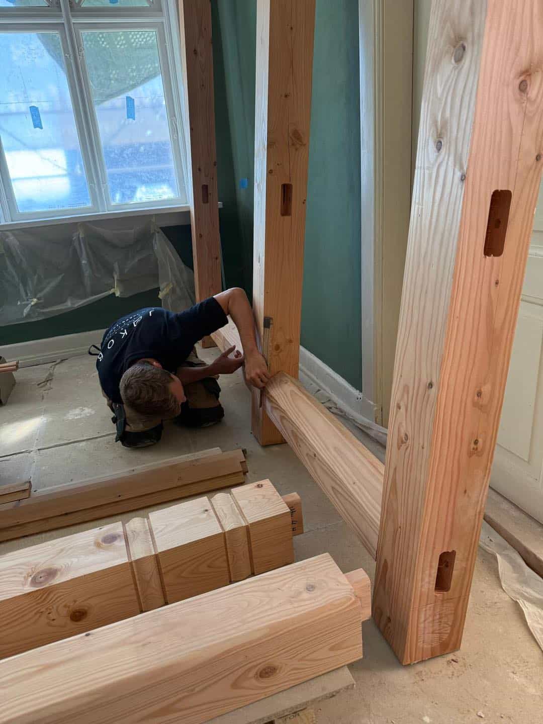 Tømrer arbejder med træbjælker i et nyt byggeri.