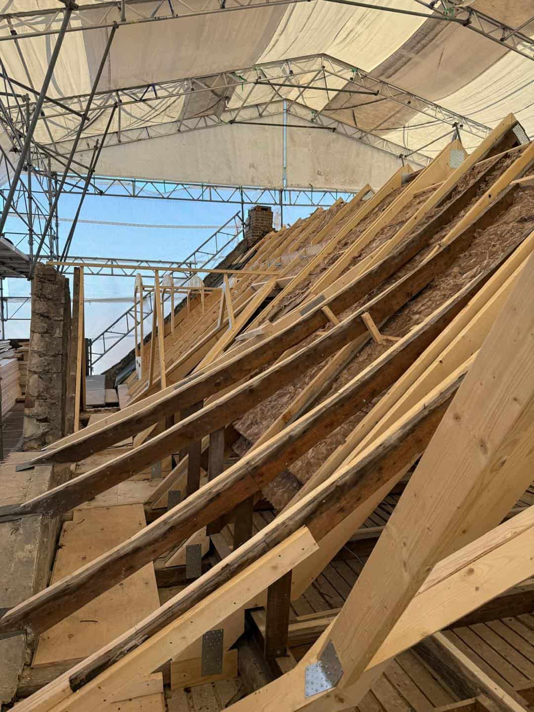 Udskiftning af tag på en ældre ejendom under renovering med træspær og undertag.