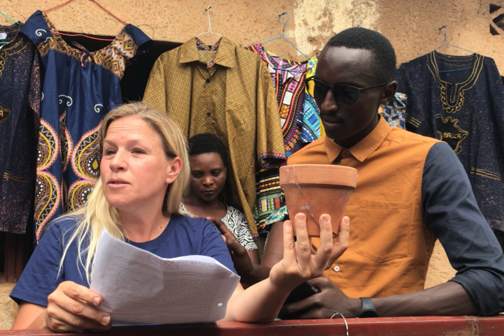 Woman speaking at cultural market with African textiles in background.