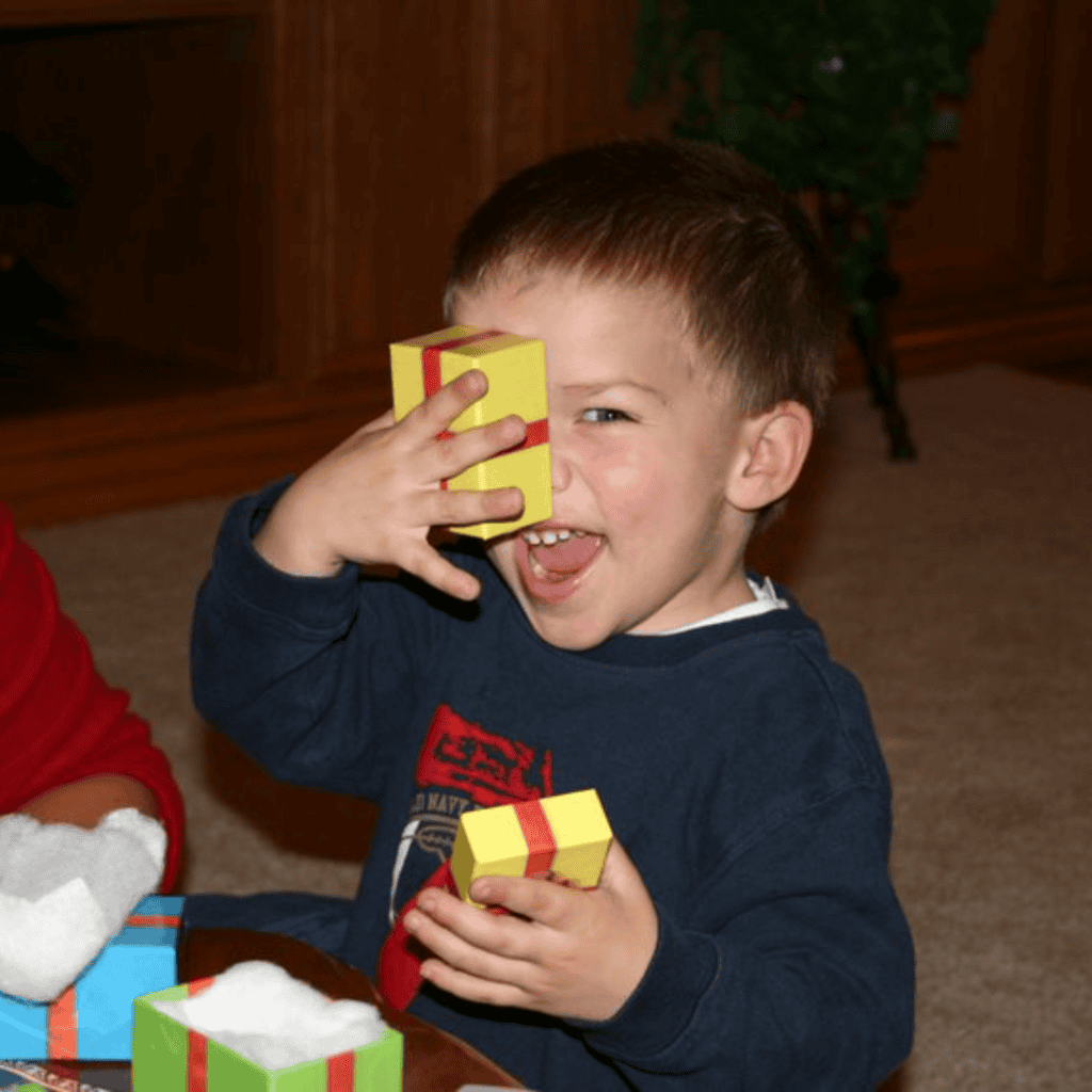 Happy boy opening a Christmas gift with a big smile.