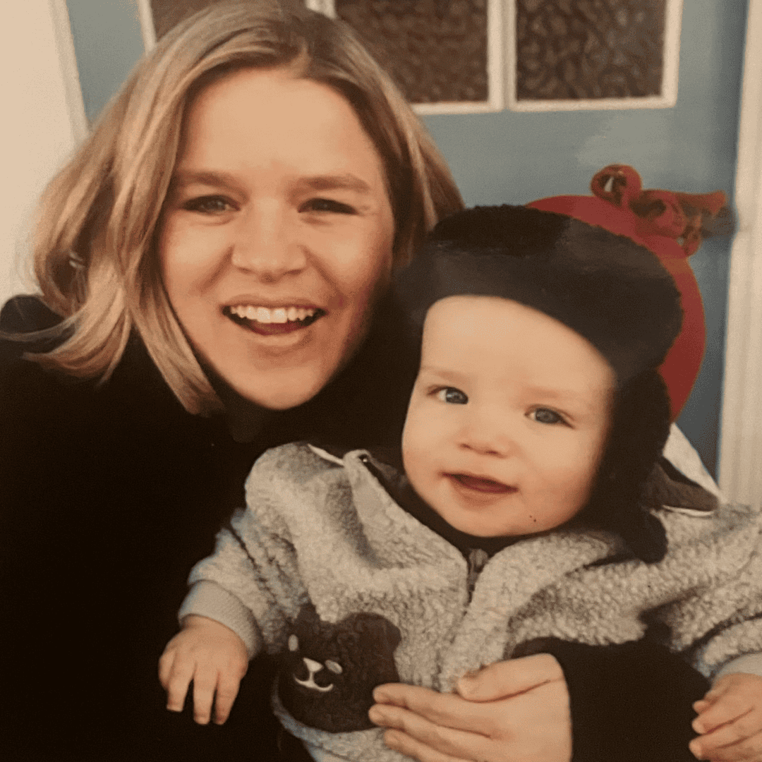 Happy woman holding smiling toddler in cozy home setting.