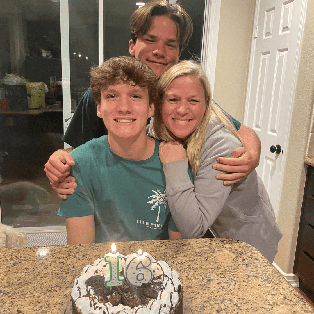 Happy family celebrating a 16th birthday with cake and hugs.
