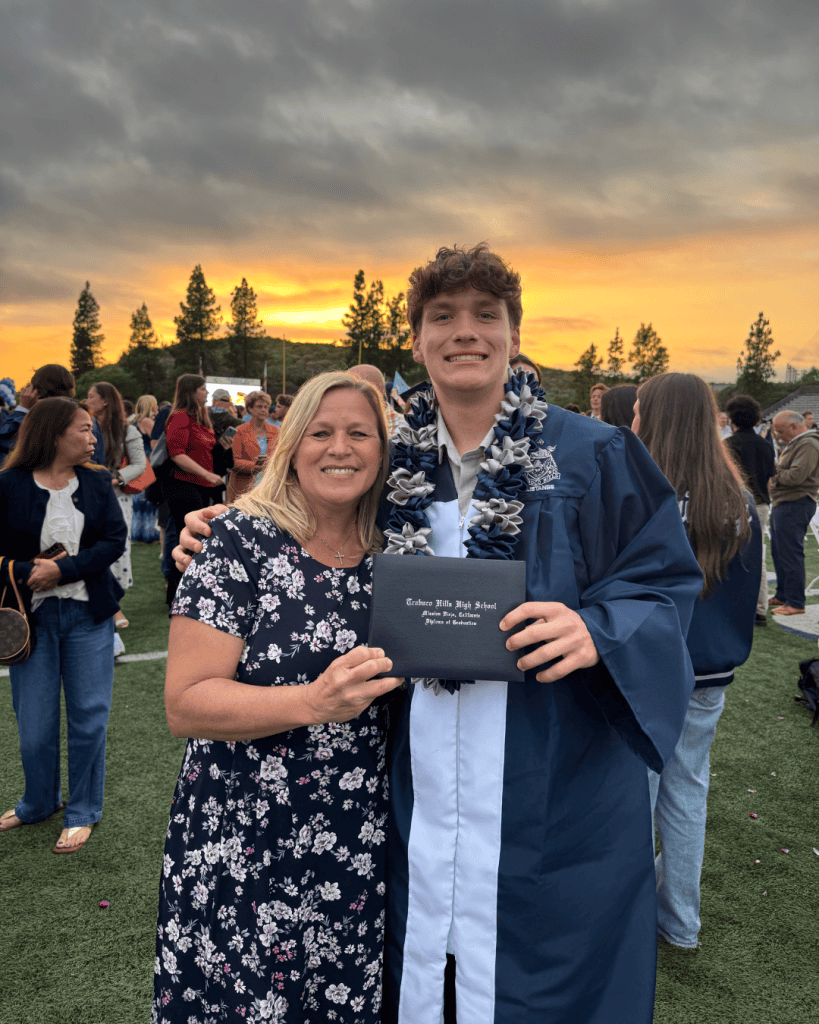 Happy graduate with mother at sunset graduation ceremony.