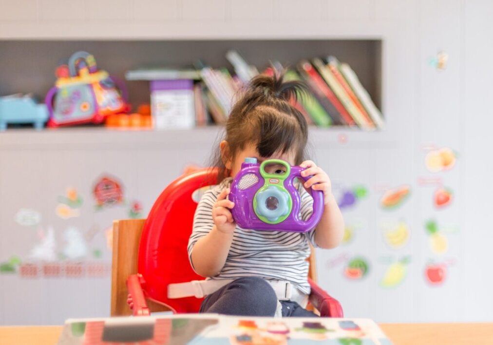 Child playing with a toy camera at Karen's Stars Childminding.
