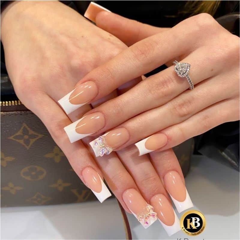 Schöne French Maniküre mit Blumenakzenten auf den Nägeln, perfekt für elegante und stilvolle Looks.