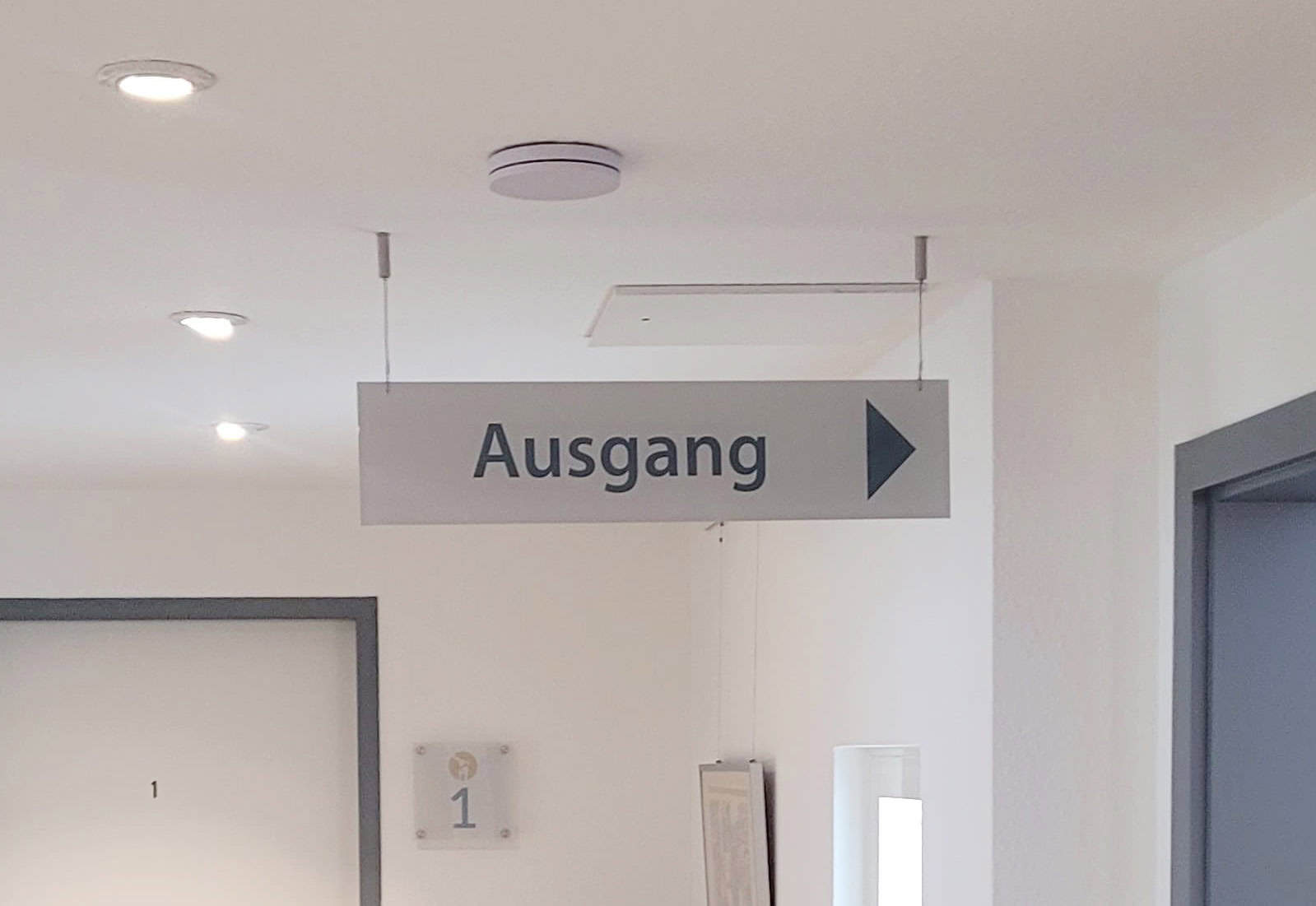 Hängendes Schild mit "Ausgang" in einem modernen Gebäude.