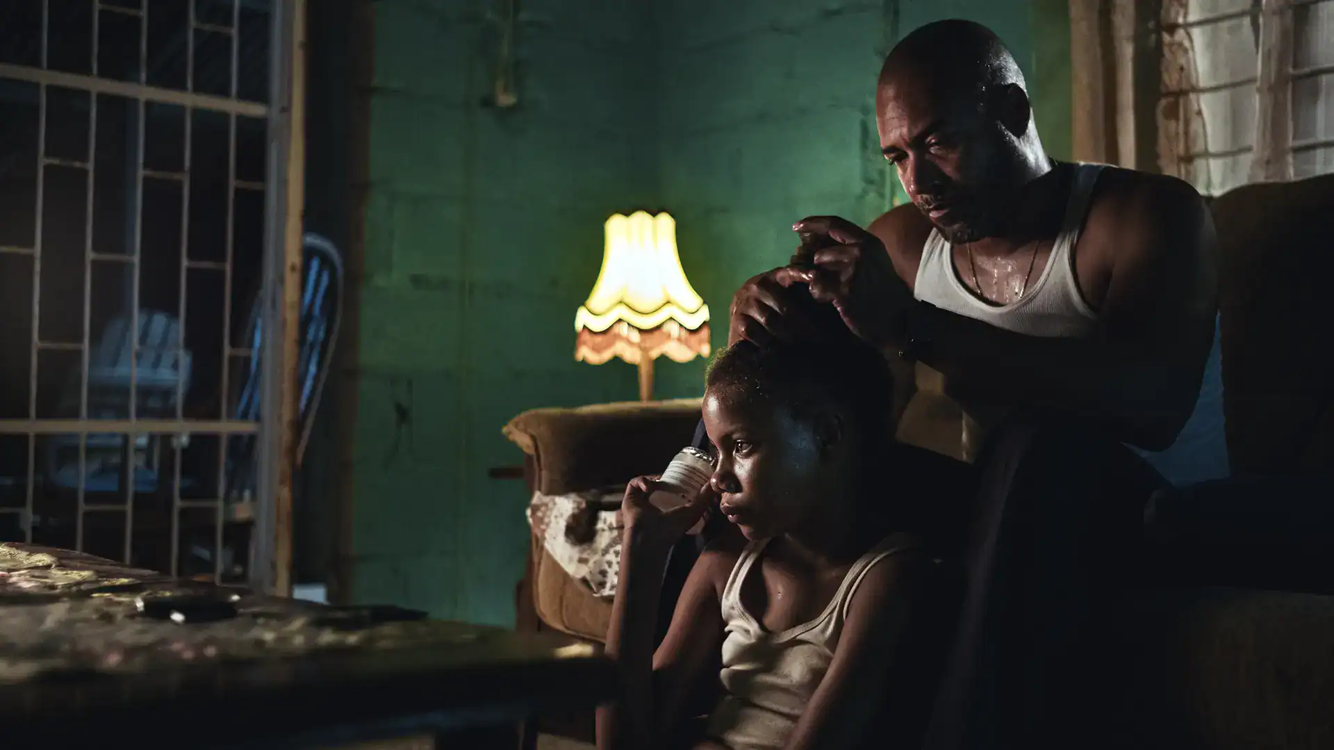 Father comforting daughter in a dimly lit room, capturing a heartfelt moment.