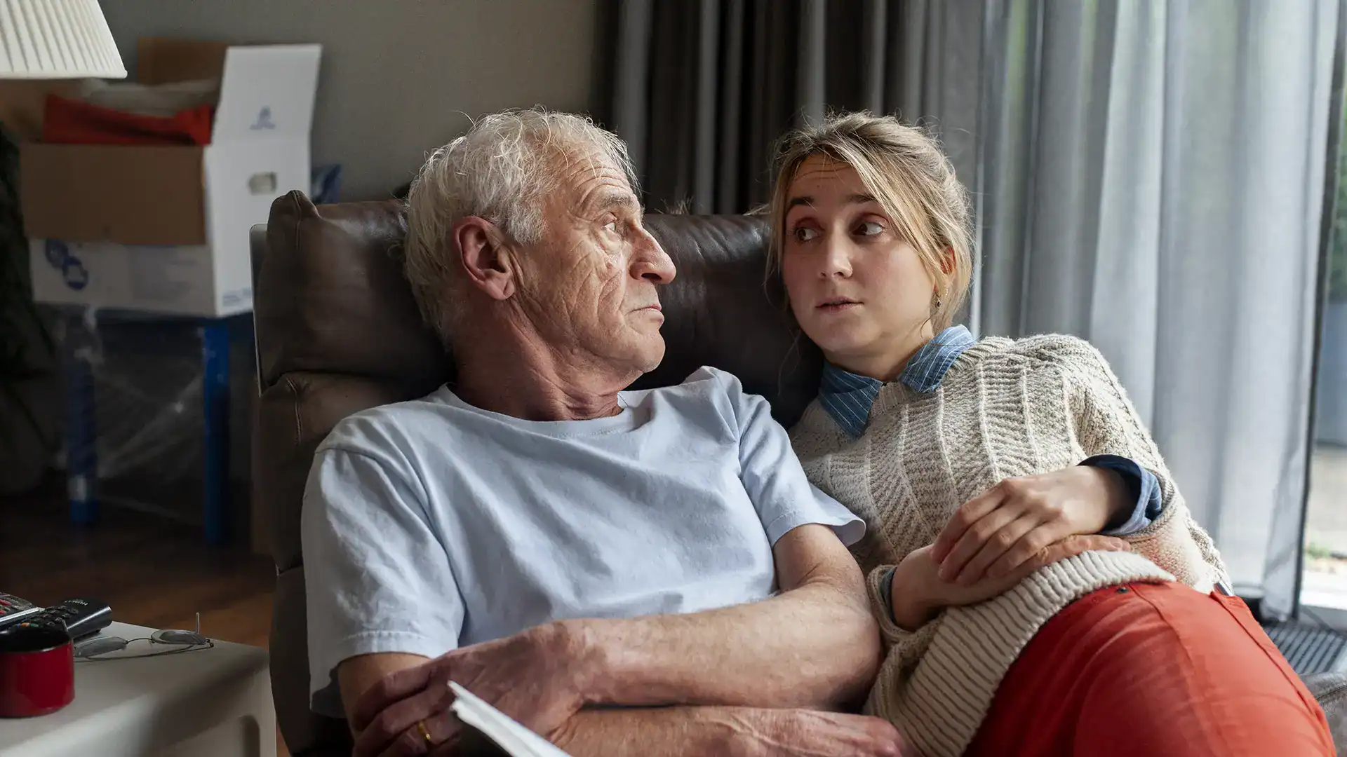 Elderly man and young woman sharing a heartfelt moment indoors.