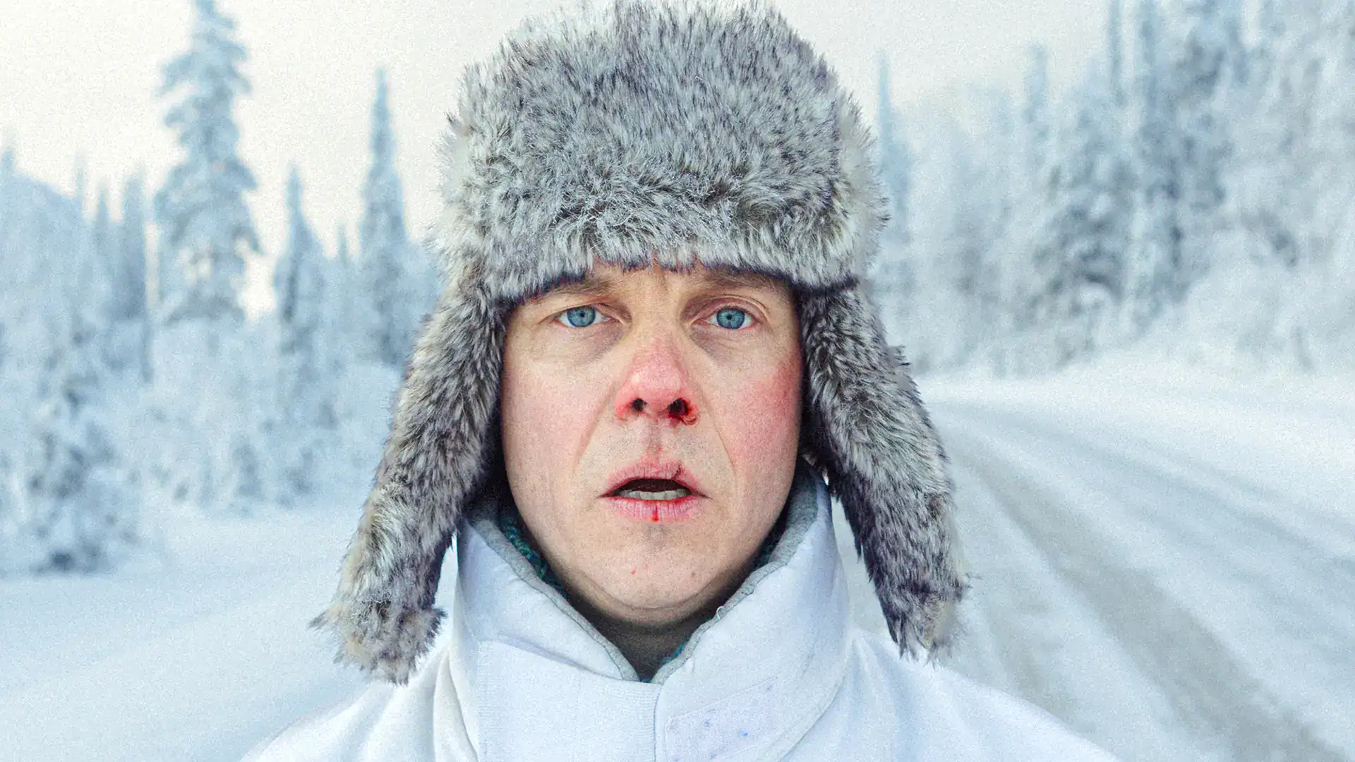 Man in winter clothing with fur hat in snowy landscape.