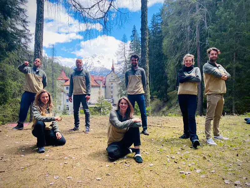 Filmmaking team in a forest with a castle backdrop, showcasing outdoor production work.