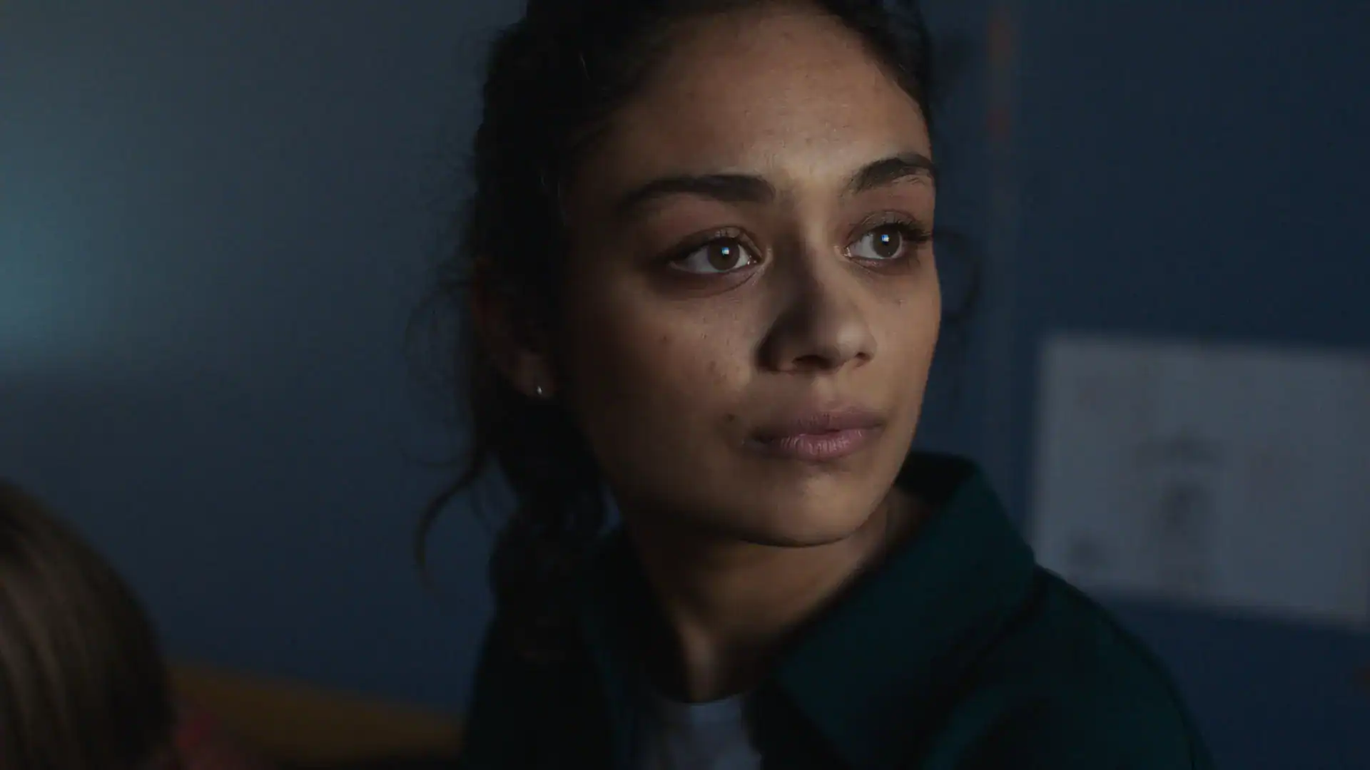Woman in a dark room with focused expression, possibly during a film shoot or interview.