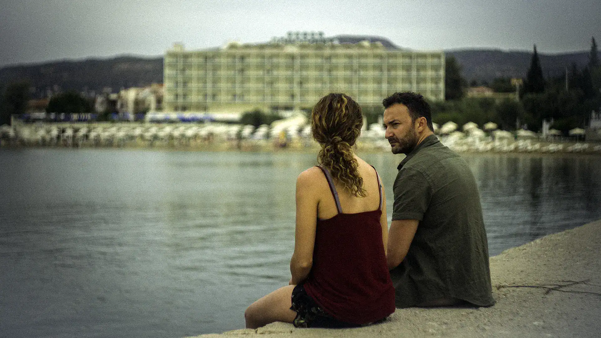 Couple enjoying a romantic moment by the water with a cityscape in the background.