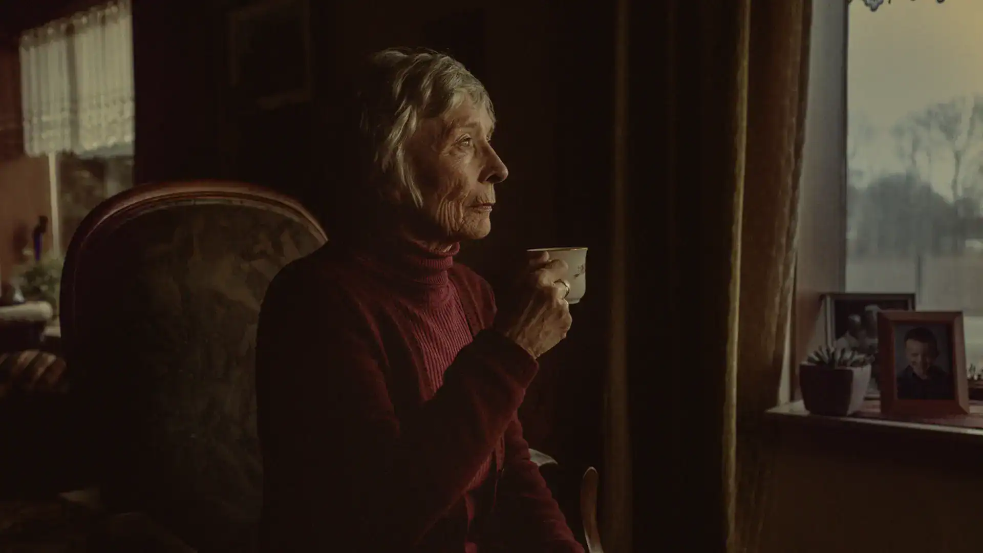 Elderly woman enjoying tea in cozy home setting.