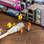 miniature engineers worker plugging in lan cable in computer