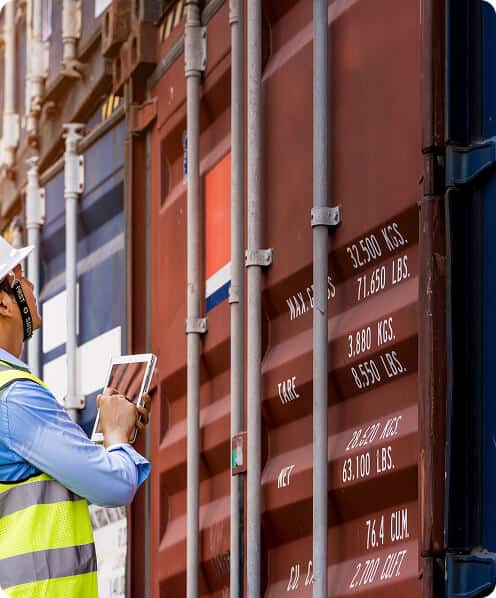 A person holding a notepad while inspecting a shipping container