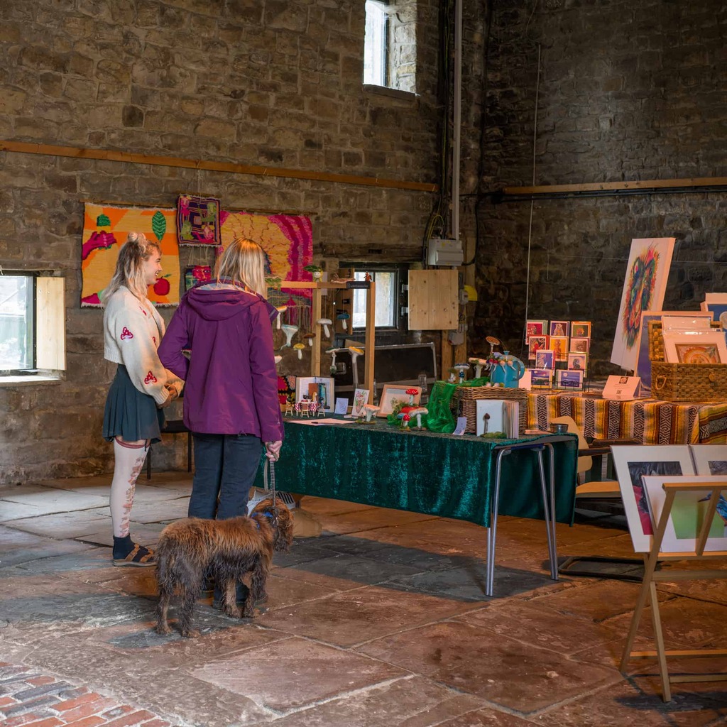 Visitors and their dog look at craft stalls in Hollybush