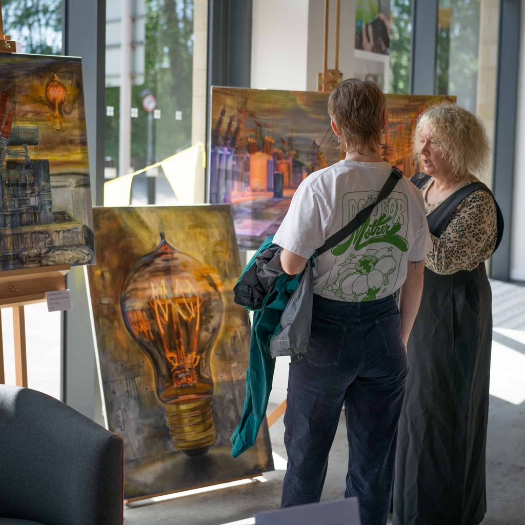 Two people looking at large paintings