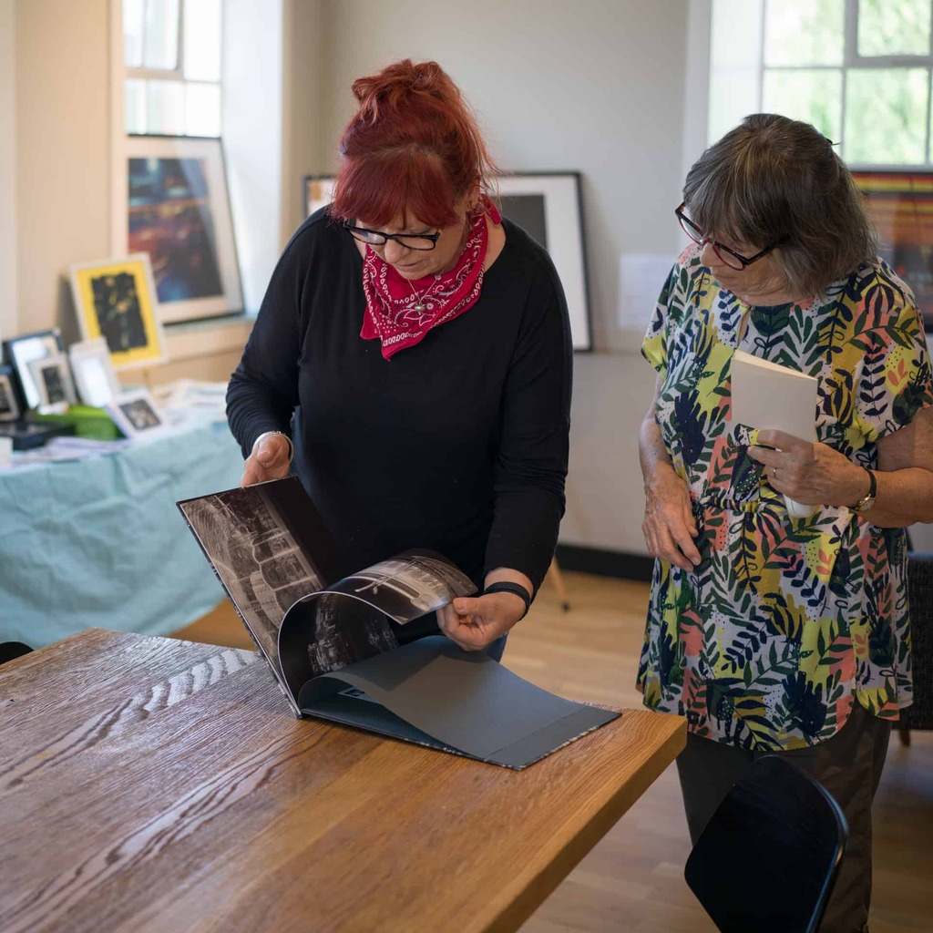 Two people looking through a photography book.