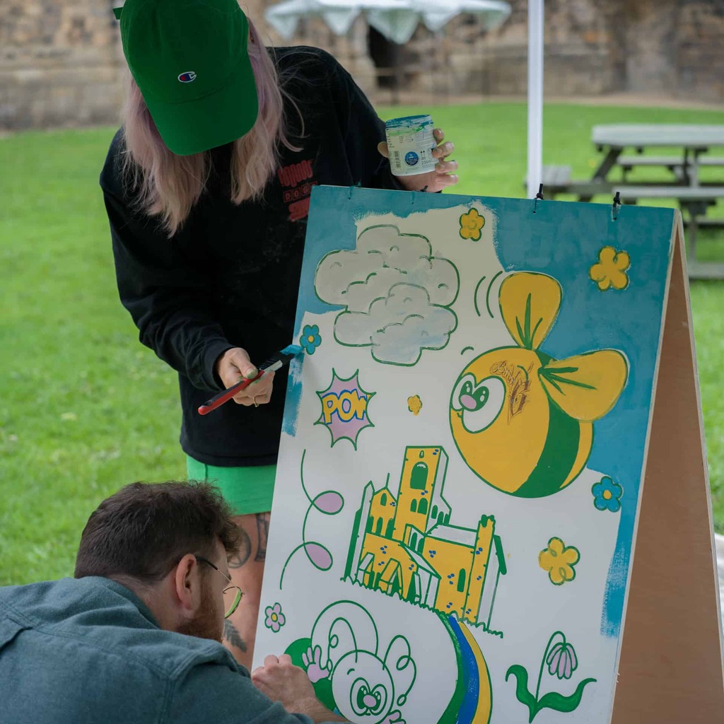Two artists painting a board