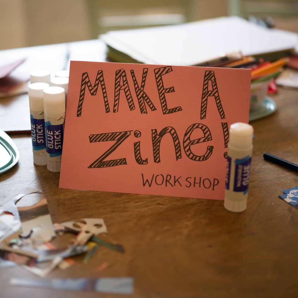 A workspace with a sign reading, 'make a zine'.