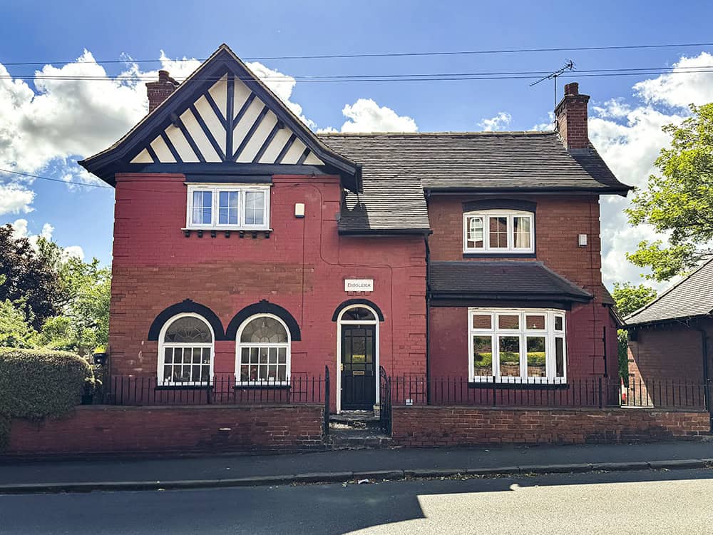 The exterior of 3 Hesketh Road. A red brick detached house with steps leading up to a black front door.