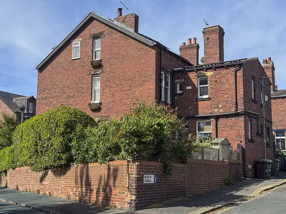 Exterior of 13 Hesketh Avenue, an end terrace red brick Victorian house, with a wooden gate into the back garden.