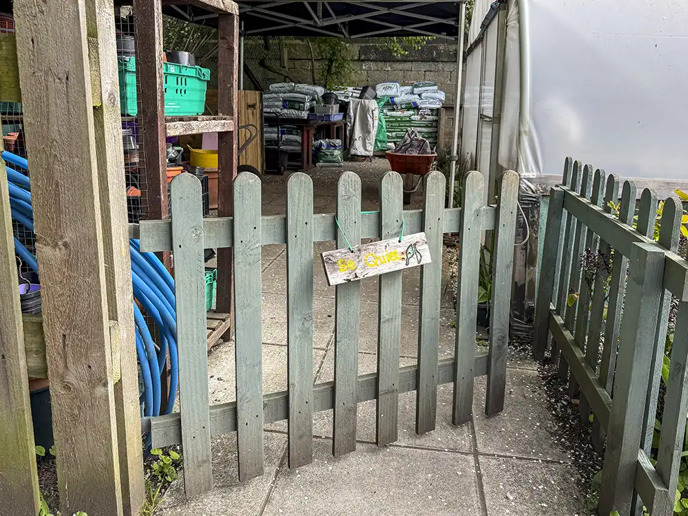 Exterior of Hollybush Conservation Centre, with a wooden gate entrance to the quiet space.