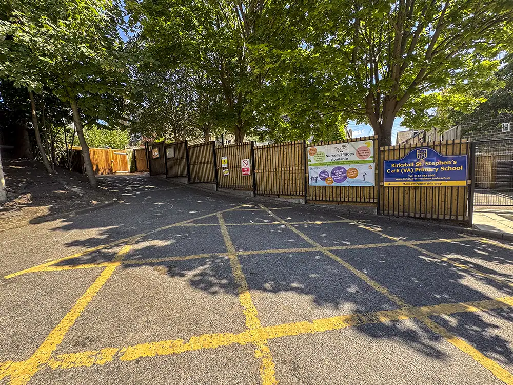 The main approach and entrance to Kirkstall St. Stephen's C of E Primary School, with the school's name sign, a KAT venue marker, and a directional arrow to the main entrance.