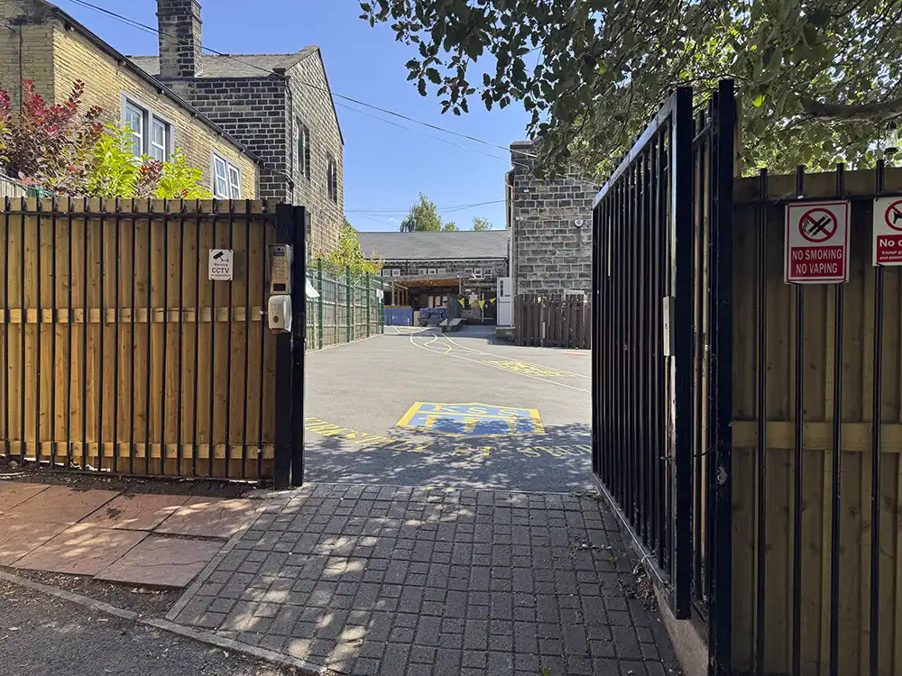 The open gate leading into the school playground, with the KSS logo painted on the tarmac.