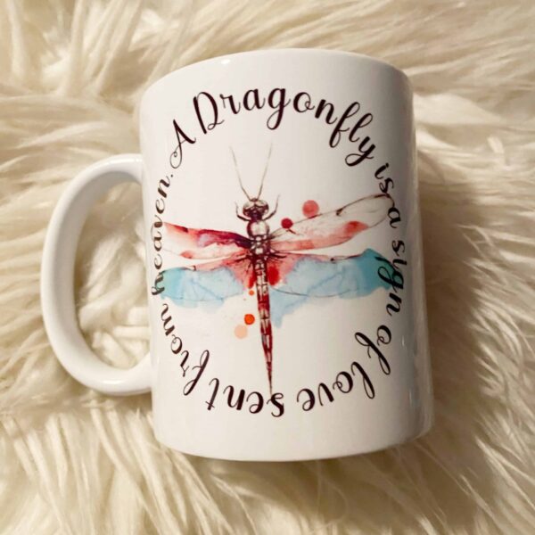 The Dragonfly love from heaven mug features a colorful dragonfly and the phrase A dragonfly is a sign of love sent from heaven in a circular pattern—perfect for anyone who believes in the magic of dragonflies.