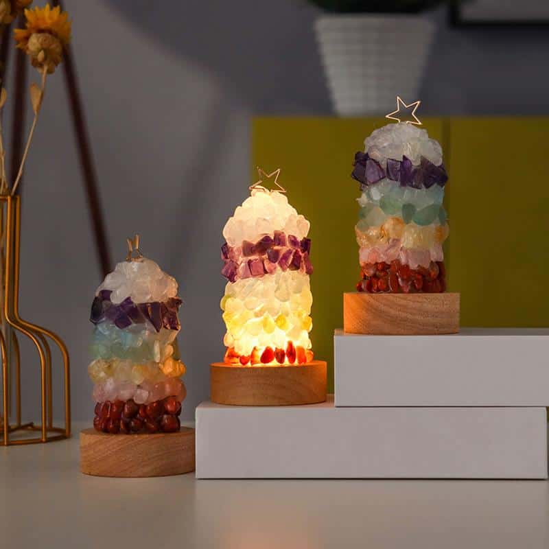 Three vibrant Crystal Lamps with star-shaped toppers sit on wooden bases; the middle Crystal Lamp glows warmly. All are displayed on a white surface against a softly blurred background.