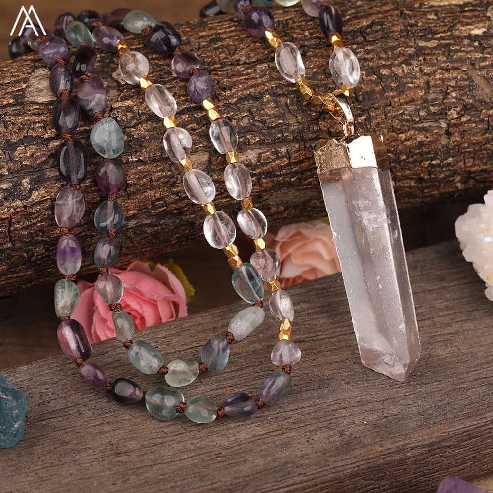 Close-up of the Natural White Quartz Stick Point Pendant Rainbow Fluorite Stone Chip 108 Prayer Beads Knotted Handmade Necklace N0280AMCD on a wooden surface, surrounded by decorative stones and artificial flowers.