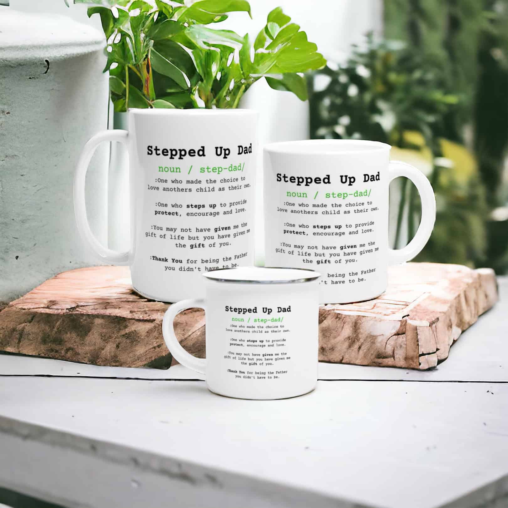 Three Stepped Up Dad Mugs featuring a witty definition in black and green text are arranged on a white table next to green plants and wooden decor.