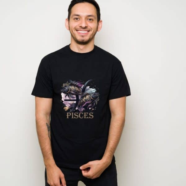 A smiling man stands against a plain light wall, wearing the Pisces Fish Tshirt with an artistic zodiac design and PISCES in gold letters below.