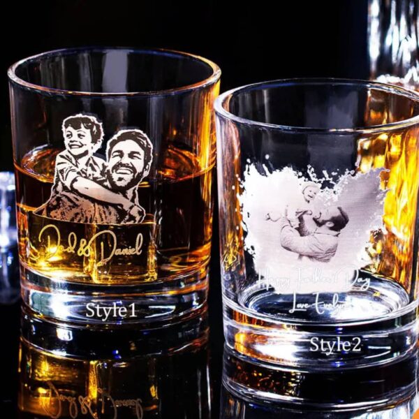 Two Engraved Photo Whiskey Glasses with drinks: the left glass features a custom image of a man carrying a child and the names Dad & Daniel; the right reads Happy Father’s Day, Love Luke with an etched man holding a child.