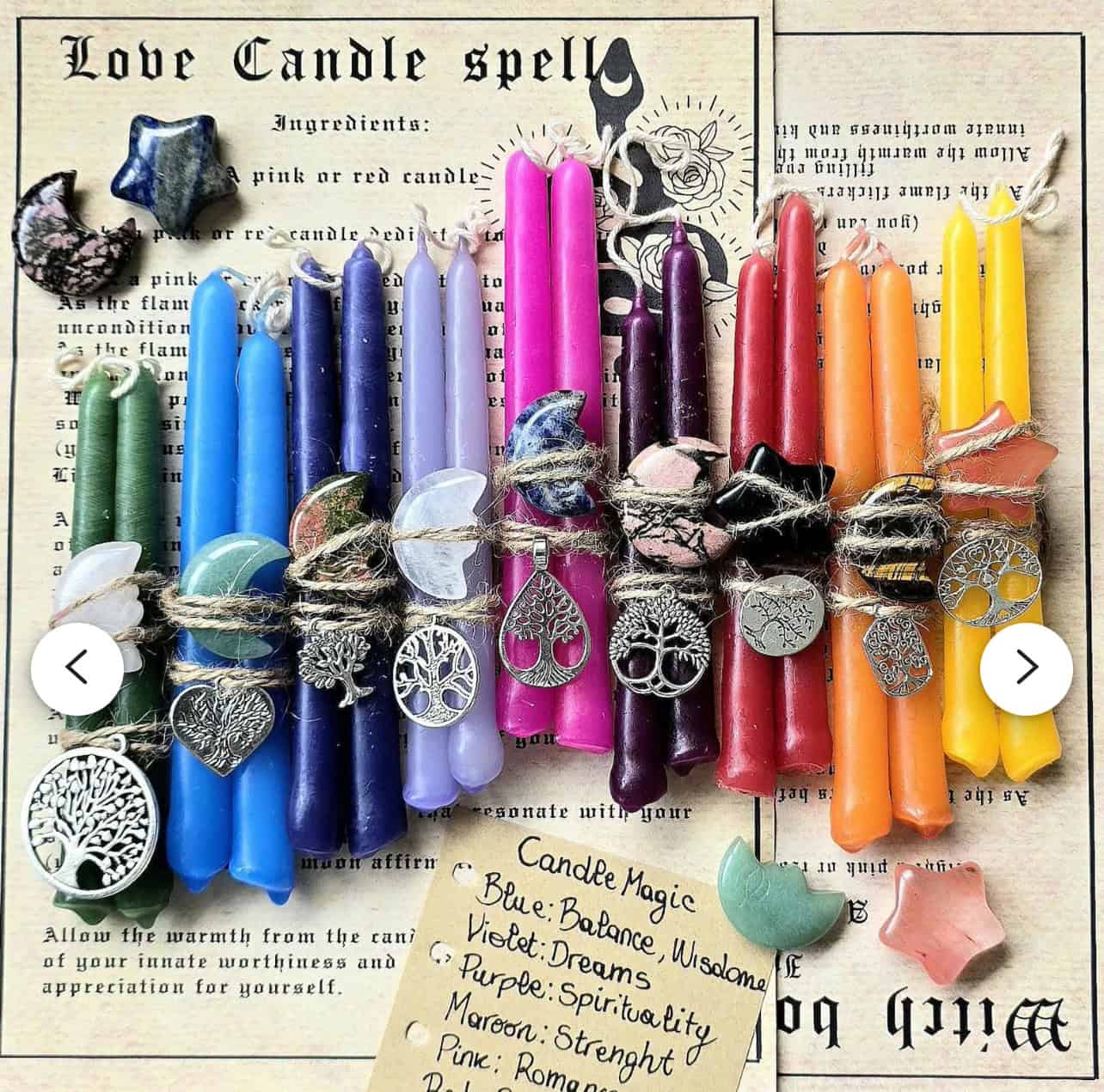 Small Intention Spell Candles, paired with crystals and charms, are arranged atop a Love Candle Spell paper featuring mystical symbols, a spell recipe, and candle magic meanings in the background.