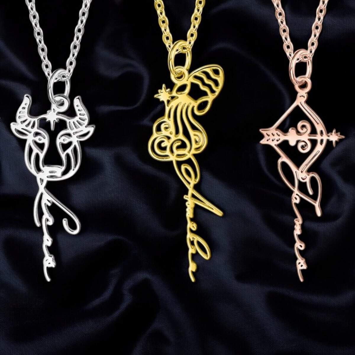 Three Personalised Zodiac Sign Sterling Silver Necklaces on a black background: a silver Taurus, a gold Virgo with butterfly detail, and a rose gold Sagittarius—each with their zodiac name in elegant cursive.