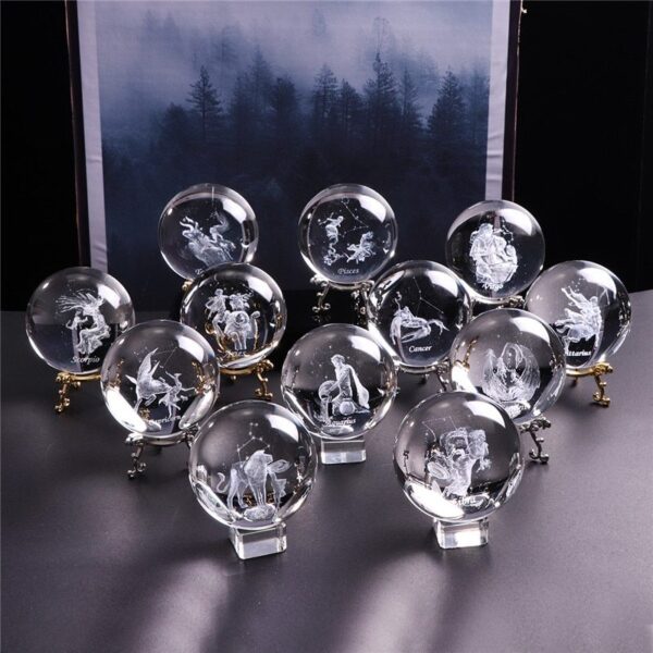 Twelve glass or crystal balls, each engraved with a different zodiac sign, are arranged on stands in front of a misty forest backdrop.