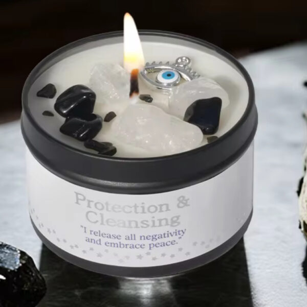 The Peace & Protection - White Sage & Frankincense Candle, adorned with black and white crystals and an evil eye charm, sits beside White Sage and a black stone—ideal for rituals promoting peace and protection.
