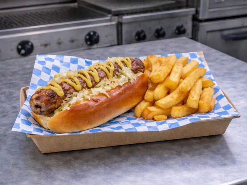 Traditional Bavarian bratwurst in a baguette with mustard at a KK Catering event.
