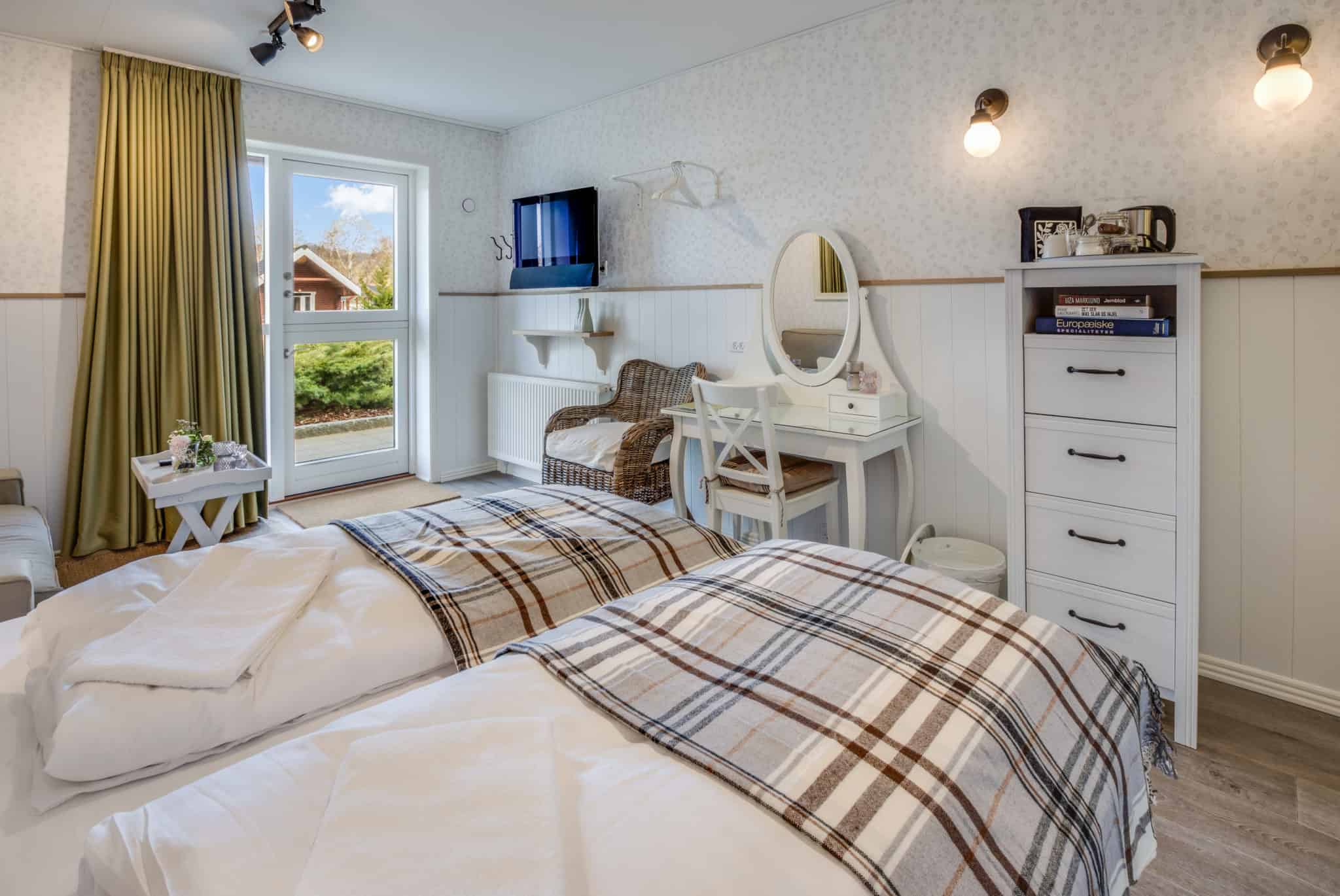 Hyggeligt værelse med seng, balkon og komfortable møbler på Knudhule Badehotel.