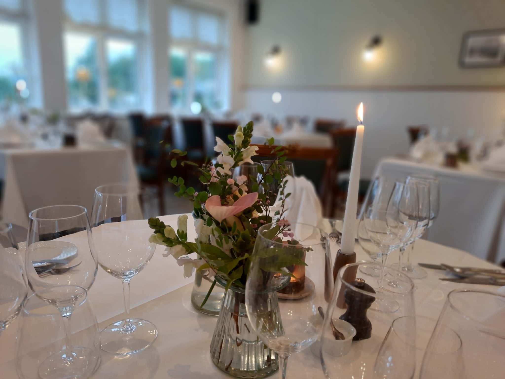 Elegant middagsborde med blomsterdekoration og stearinlys på Knudhule Badehotel.