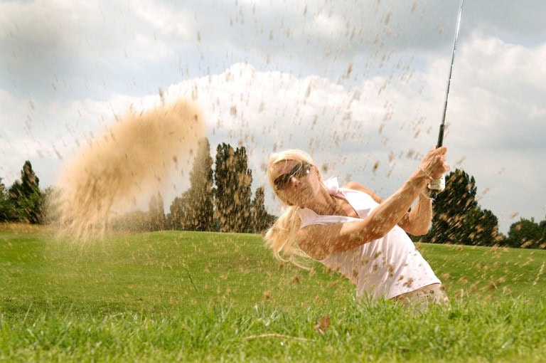 Eksponerede badeslag, kvinde spiller golf med sandkasse, strandclima, sommeraktiviteter, fritidsfornøjelse, golf på stranden, afslapning ved havet.