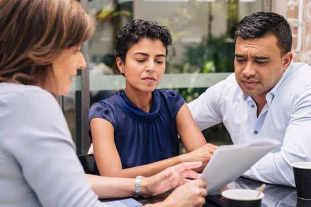 a group of people sitting at a table looking at a paper
