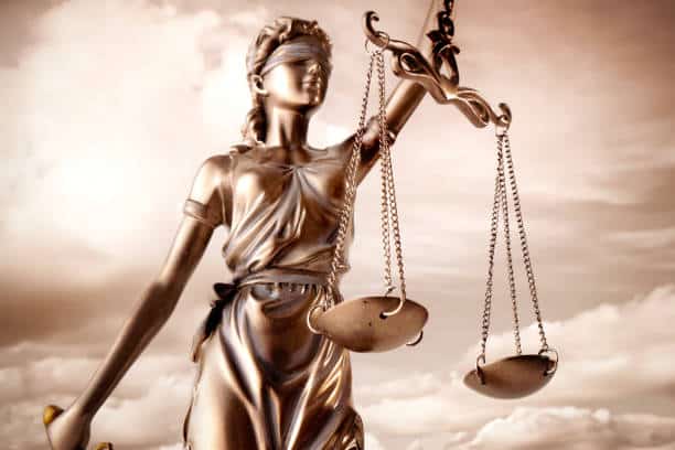 Environmental Crime Lawyers Statue of Lady Justice holding scales of justice against a beautiful cloud background of Types of Criminal Lawyers