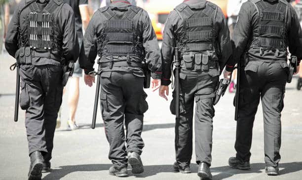 Four policemen with anti-riot uniform patrolling the city