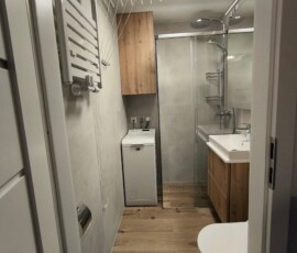 Czarna matowa rama kabiny prysznicowej typu walk-in w małej łazience w bloku.