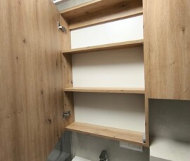 Przytulna strefa umywalkowa w bloku z podświetlanym lustrem, czarnymi akcesoriami i dekoracją roślinną.